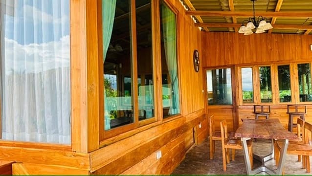 A long teak dining hall with a warm chandelier — quiet, dim, slow.